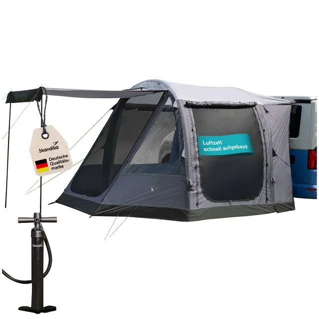 Ein graues Wohnmobilzelt mit mehreren Fenstern, einem Markisenbereich und einem Aufkleber. Daneben steht eine Pumpe.