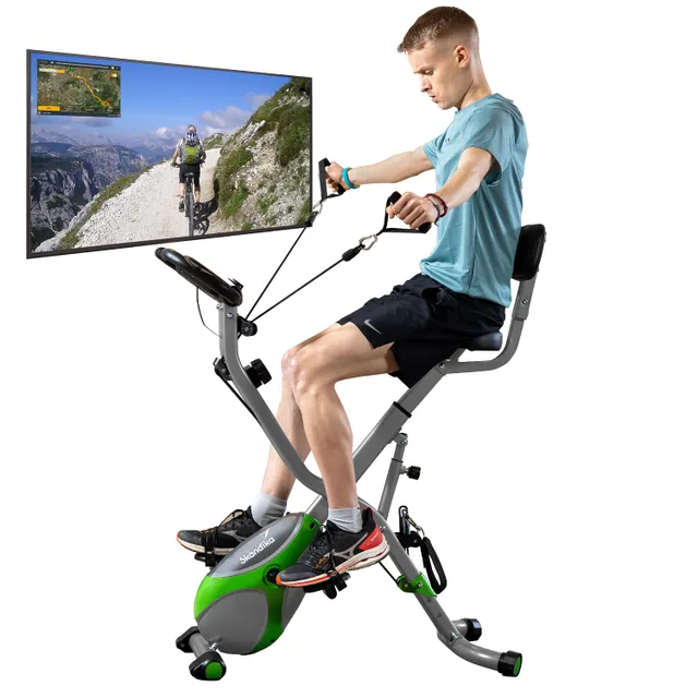 Ein Mann sitzt auf einem Heimtrainer mit einer Bildschirmansicht einer Radfahrstrecke in der Natur. Er benutzt Haltegriffe und Pedale.
