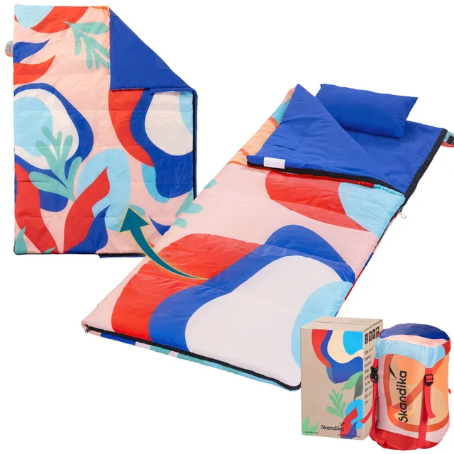 Bunte Schlafunterlage mit grafischem Muster, Kissen und Verpackung daneben.