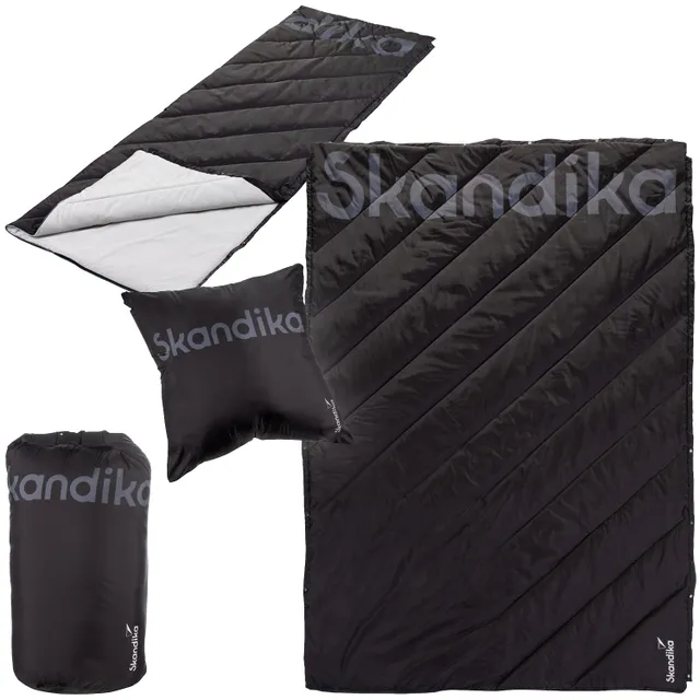 Schlafsack und Kissen in Schwarz mit diagonal verlaufenden Nähten. Schlafsack ist umgeschlagen, darunter helle Innenseite sichtbar.