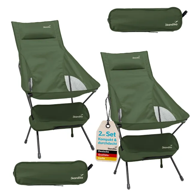 Zwei grüne Campingstühle mit Gestell, einer mit Fußstütze. Ein Stuhlabzeichen mit Angaben zur Marke und einem Packmaß ist sichtbar.