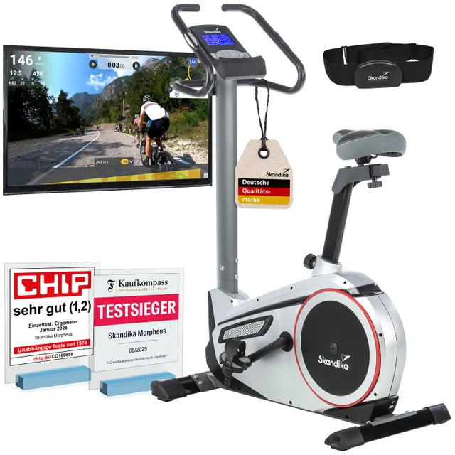 Ergometer in silberner Ausführung mit Bildschirm, Herzfrequenzgurt und mehreren Auszeichnungen im Vordergrund.