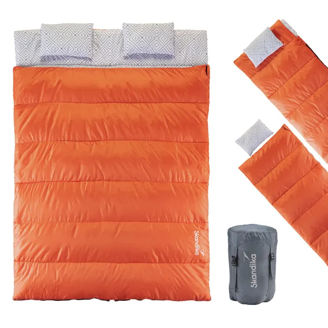 Orangene Schlafsack-Decke mit zwei Kissen oben und einem kompakten Setsack rechts. Das Material ist glatt und gesteppt.