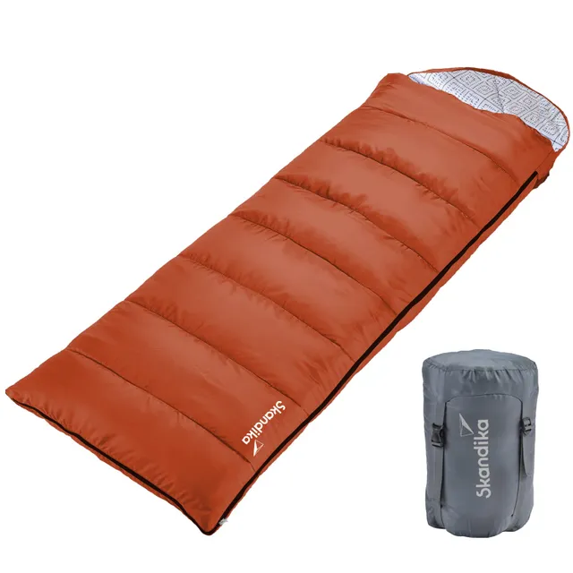 Schlafsack in Orange mit gestepptem Design und grauem Kompressionssack rechts daneben.