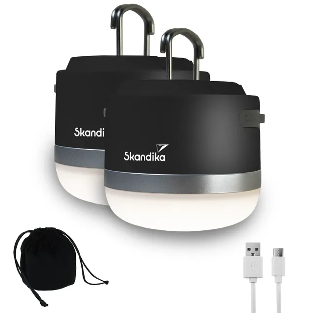 Zwei schwarze Campinglampen mit Silberelement, Aufhängemöglichkeiten und USB-Ladekabel neben einem schwarzen Beutel.