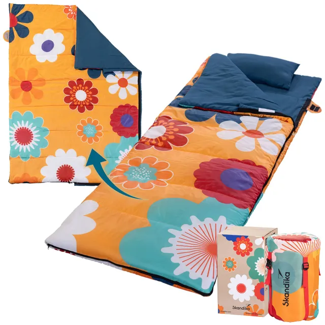Bunte Schlafsackunterlage mit floralen Mustern in Orange und Blau sowie einem Kissen, daneben ein verpackter Schlafsack.
