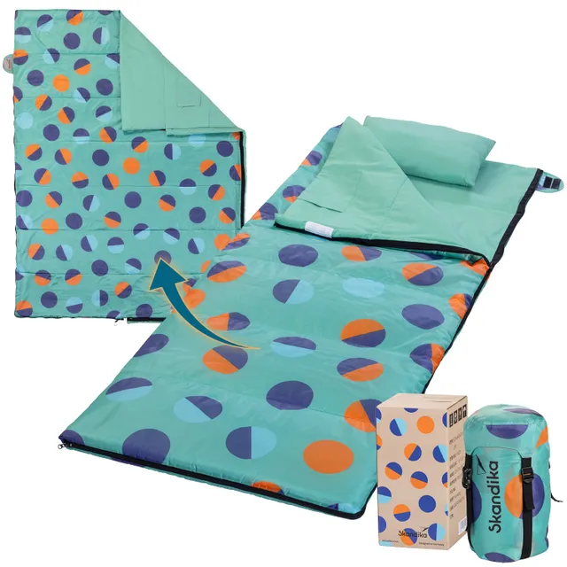 Eine Schlafsack-Decke mit bunten Punkten in Blau, Orange und Grün, teilweise gefaltet. Daneben ein Transportbeutel.